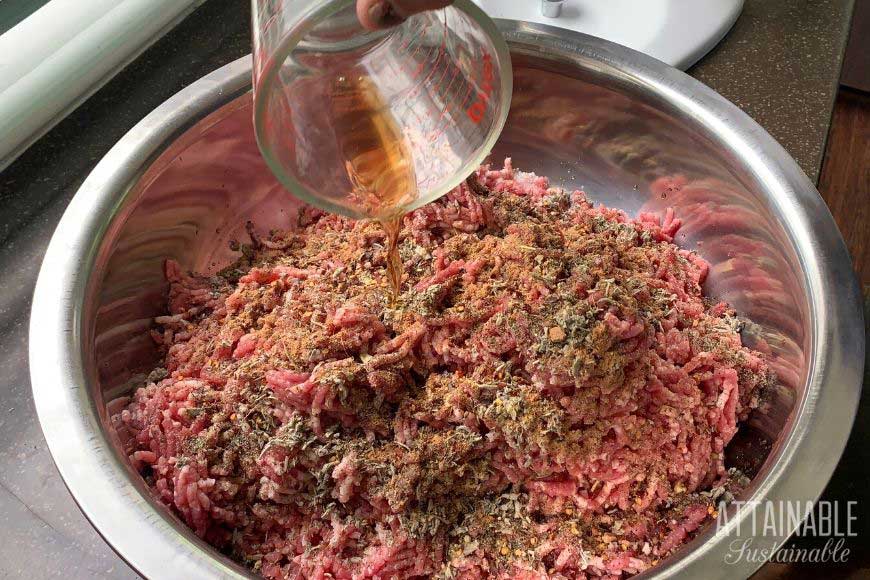 measuring cup pouring wine into ground pork