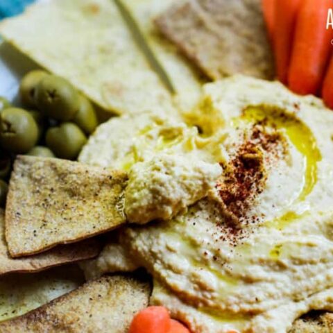 easy homemade hummus on a platter, chip and hummus in foreground