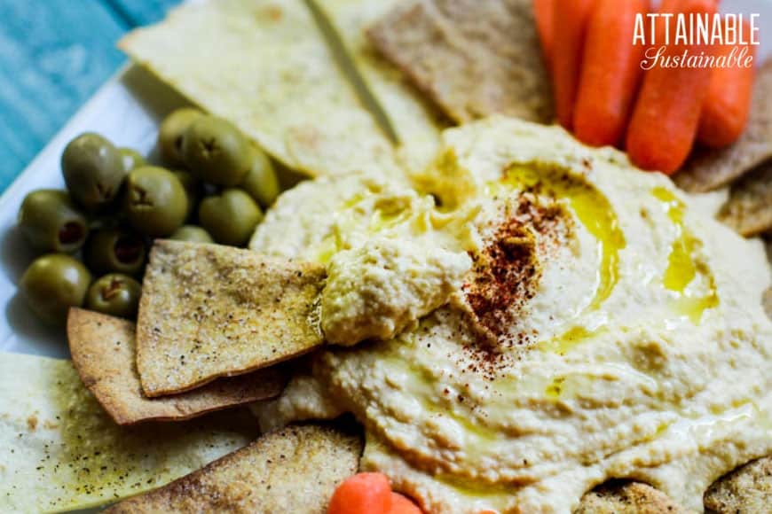 easy hummus recipe on a platter, chip and hummus in foreground