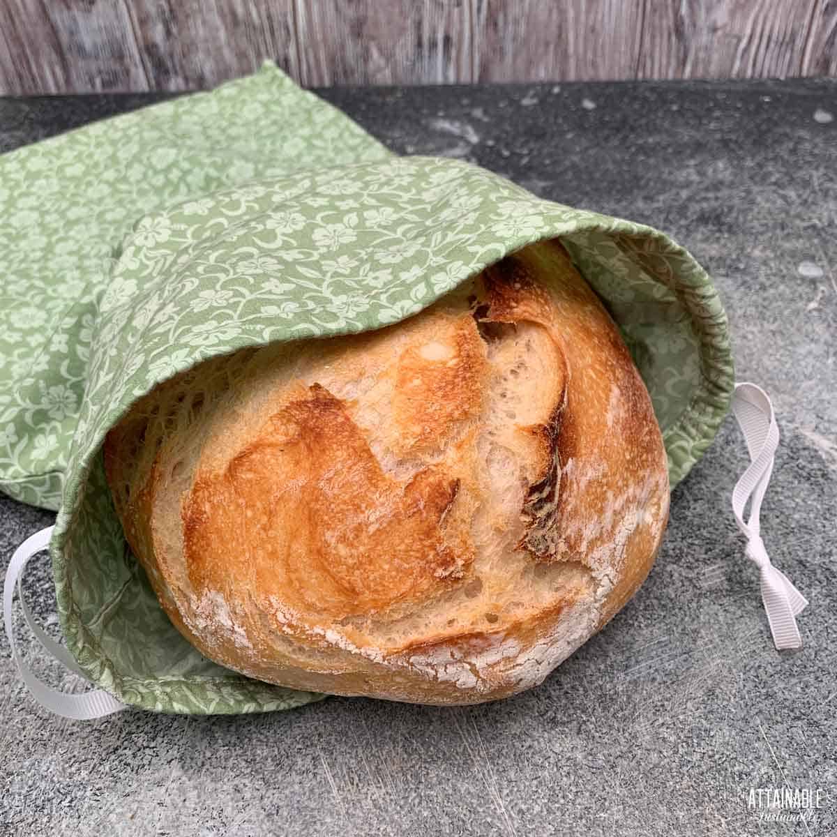 fresh loaf of bread in a drawstring cloth bag.