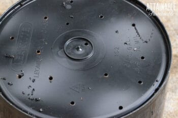 black bucket with holes drilled in bottom