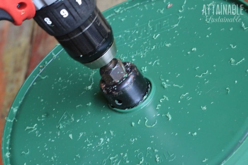 close up of hole saw drilling a hole in a green bucket