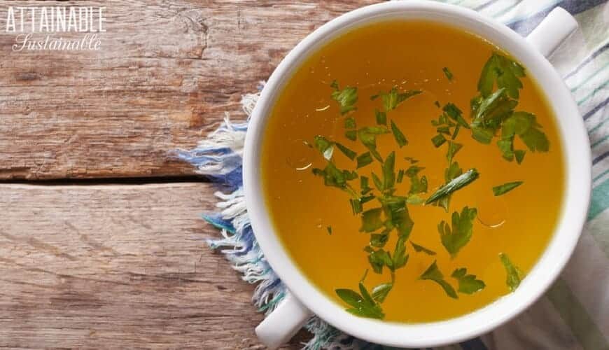 cup of broth with parsley on blue fringed placemat