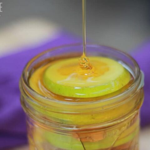 stream of honey flowing into a glass jar full of natural throat soother ingredients