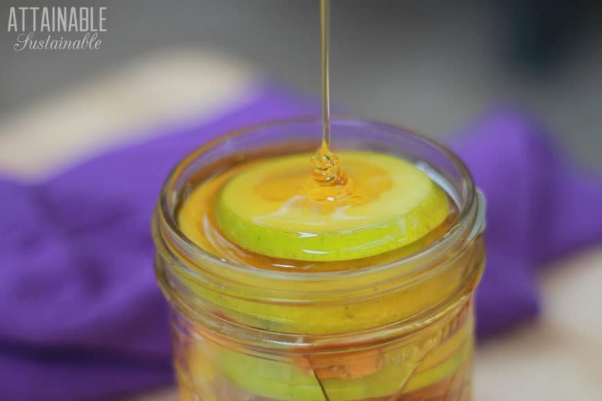 stream of honey flowing into a glass jar full of natural throat soother ingredients