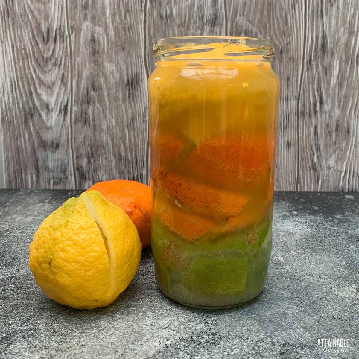jar with limes, oranges, and lemons under liquid for fermenting.