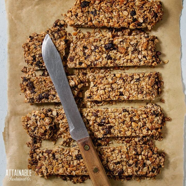 browned homemade granola bars on brown paper with a knife sitting across cut slices.