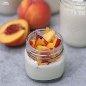 small jar with vanilla yogurt and chunks of fresh peach.