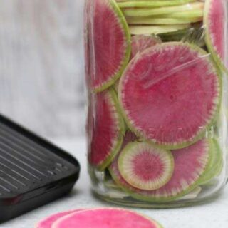 pink and green slices of a watermelon radish in a jar
