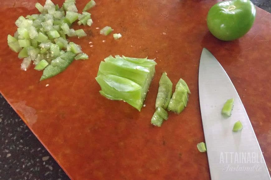 cutting board with knife showing chopping method for salsa verde recipe.