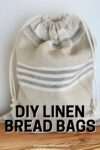 beige and white linen bread bag standing upright.