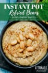 bowl of homemade refried beans with more bowls of cilantro and chopped onion on a teal background