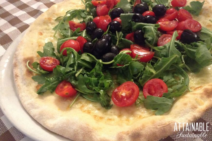 arugula, tomatoes and olives on a pizza
