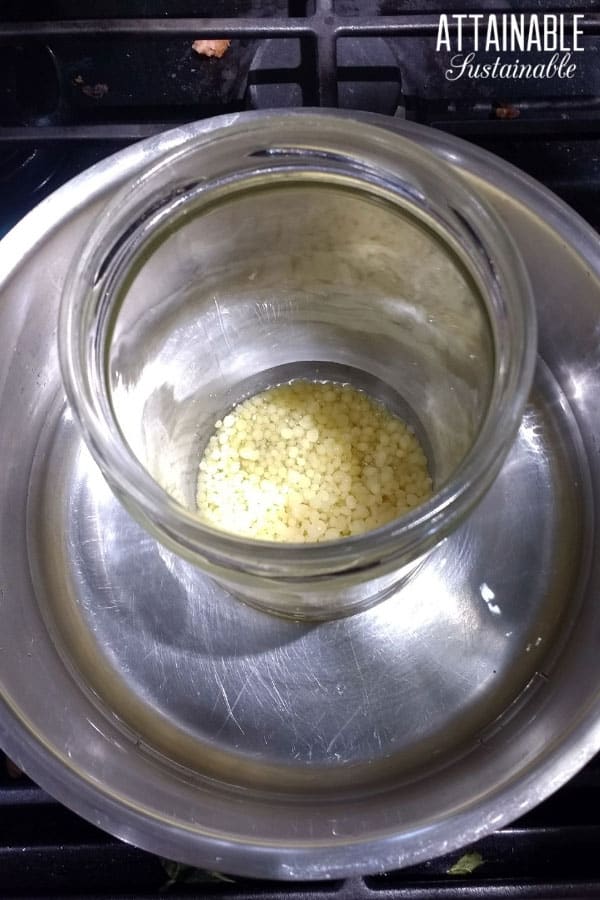 bees wax pastilles in a glass jar, inside a saucepan for a makeshift double boiler