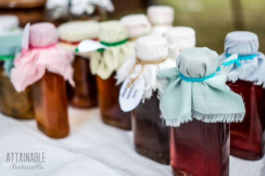 clear bottles with brown liquid, topped with pastel colored fabric