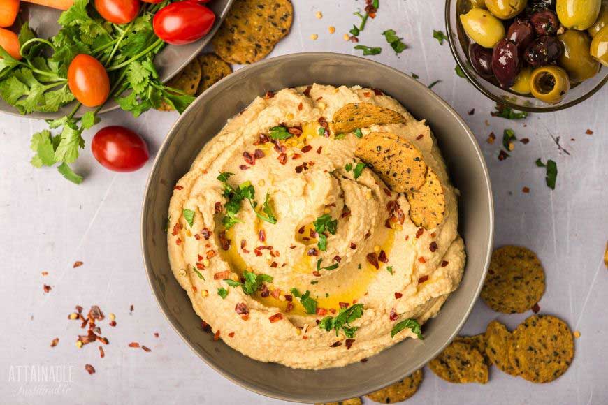 overhead photo of healthy chipolte hummus with olives and tomatoes