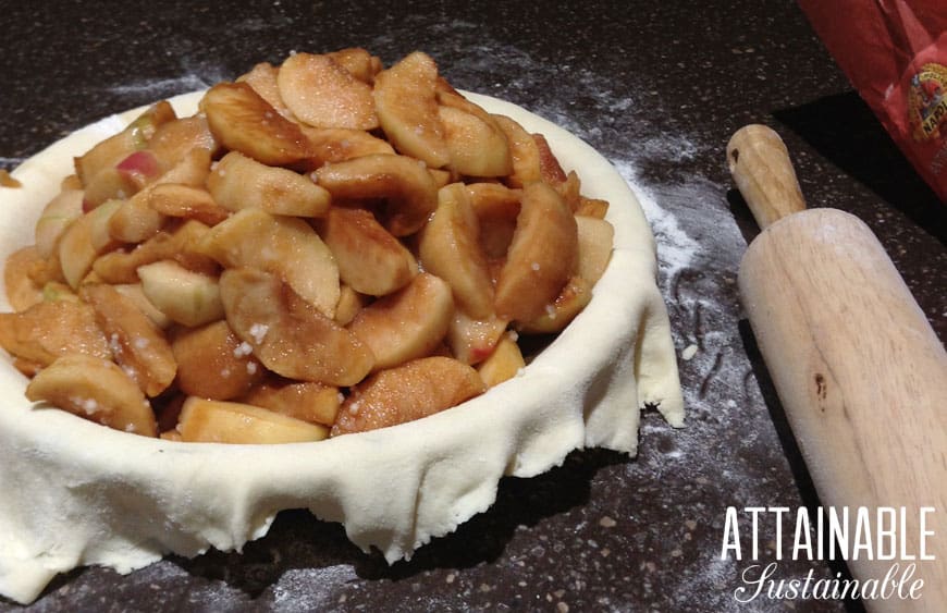 making apple pie. raw dough in pie plate with cinnamon coated sliced apples