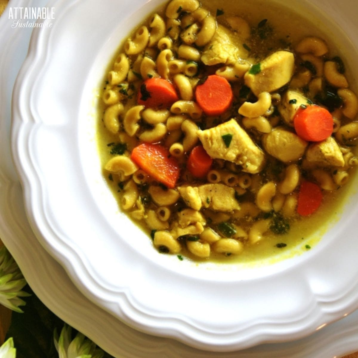 golden chicken soup in a white bowl from above.