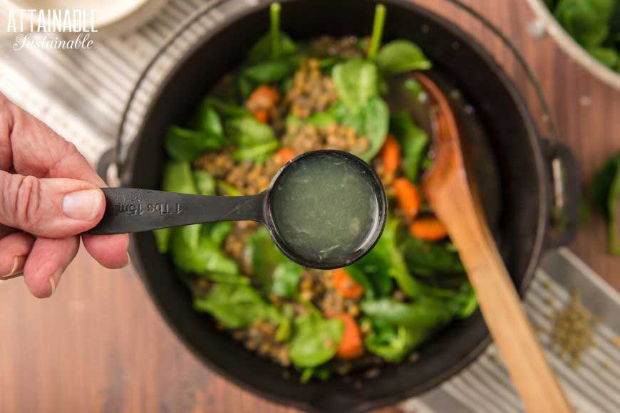 spoon of lemon juice above a pot of lentil stew