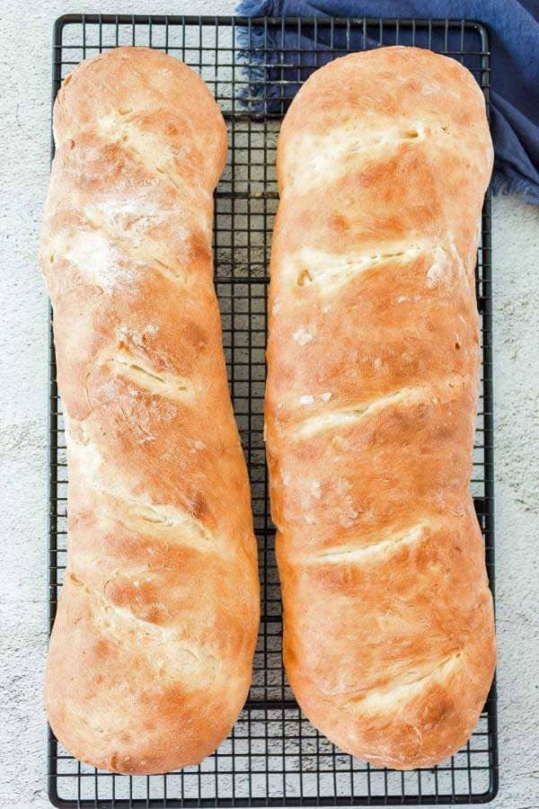 two loaves of browned french bread cooling on a wire rack