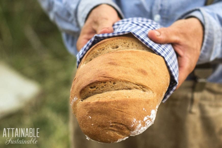 man in blue shirt holding loaf of bread