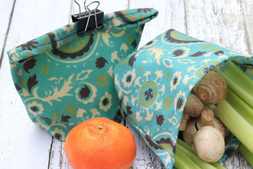 DIY reusable snack bags in a teal print, with celery, mushrooms, and a tangerine