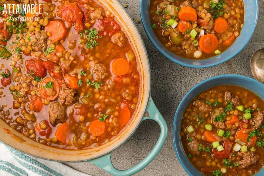 sausage lentil soup in blue pot and bowls from above.