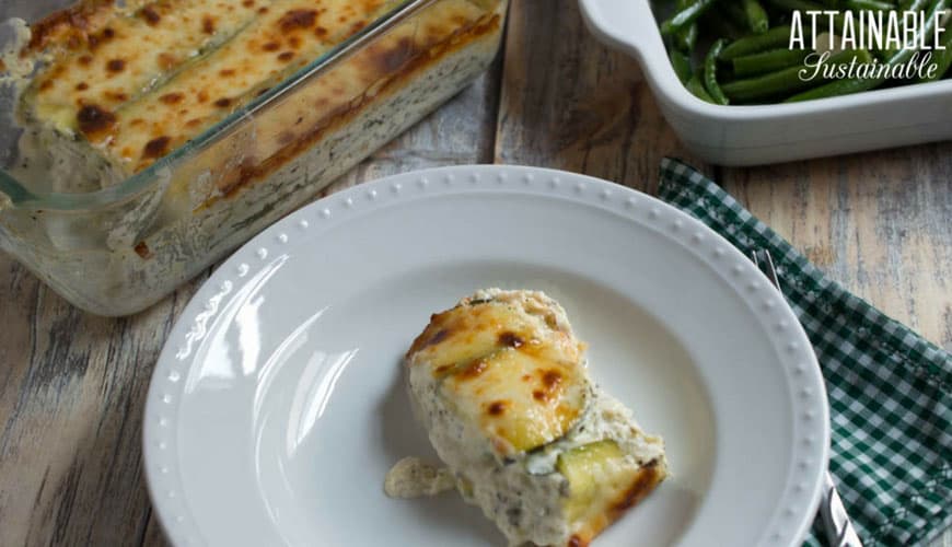 plated zucchini lasagna with glass baking dish with browned cheese on top in the background