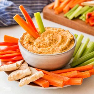 bowl of hummus with carrot and celery sticks.