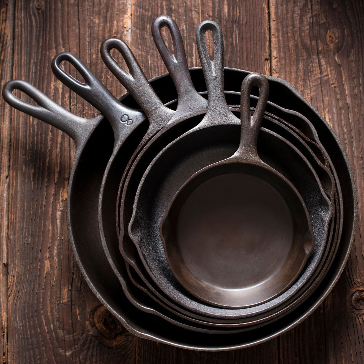 six cast iron pans in graduated sizes stacked one inside the other.