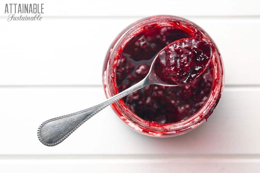 red jar of jam with a spoon scooping some, from above.