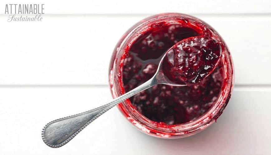 fruit preserves in a glass jar with a spoon full of the spread