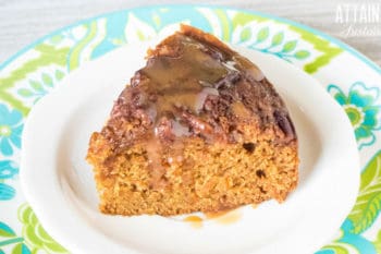 slice of applesauce cake with caramel sauce on a white plate with blue and green trim