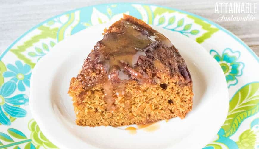 slice of applesauce cake with caramel sauce on a white plate with blue and green trim