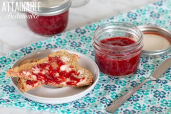 two jars of strawberry compote on a teal napkin with pieces of toast buttered and spread with compote