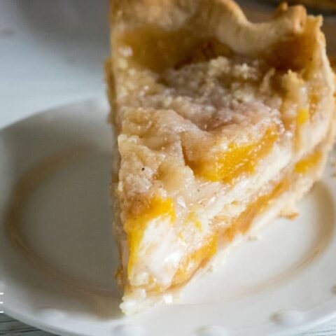 peach pie with crumb topping on a white plate