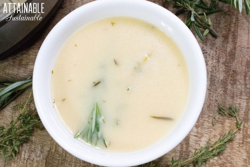 turkey gravy in a white bowl with herbs as a Thanksgiving side dish to serve with potatoes