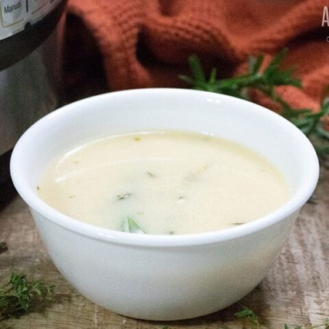 turkey gravy in a white bowl with herbs