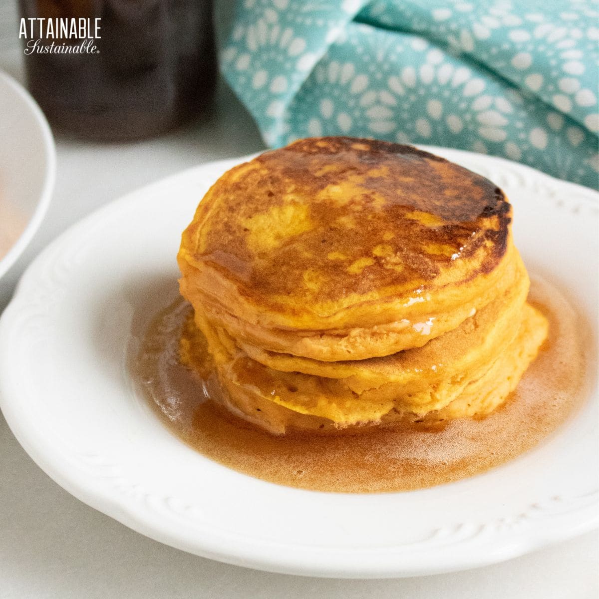 pumpkin pancakes on a white plate, with syrup.