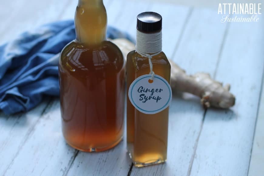 ginger simple syrup in two glass bottles with fresh ginger root