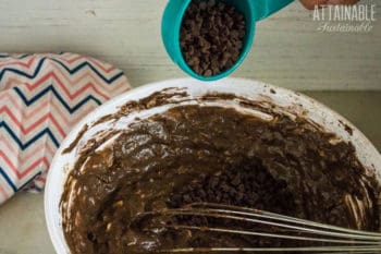 double chocolate muffins batter in bowl, with chocolate chips being poured in