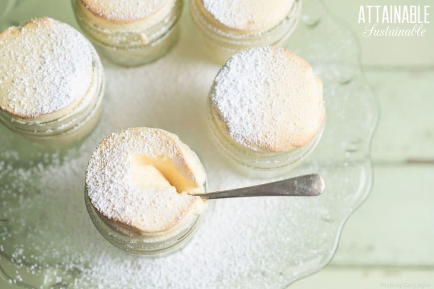 small glass jars of yellowish souffle dusted with powdered sugar