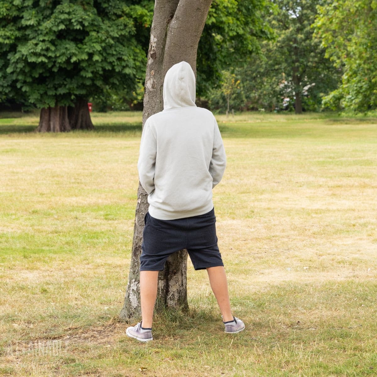 young man peeing on a tree.