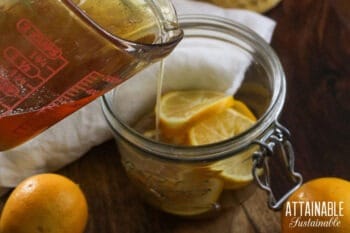 pouring honey into a jar of sliced lemons.