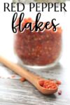 jar of homemade red pepper flakes, with some in a small wooden spoon.