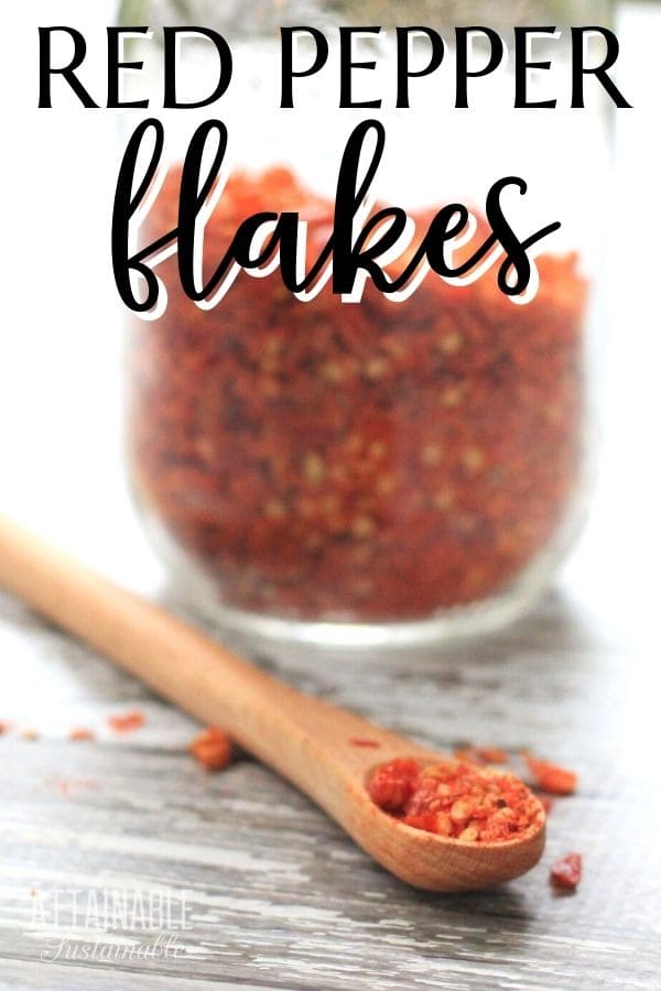 jar of homemade red pepper flakes, with some in a small wooden spoon.