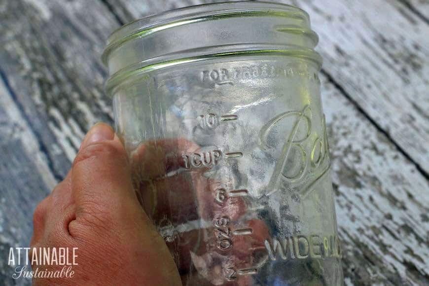 hand holding an empty Ball canning jar