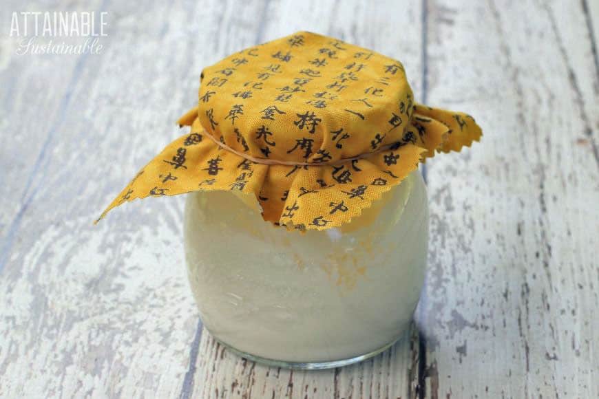 white cream in a glass jar with a yellow cloth cover