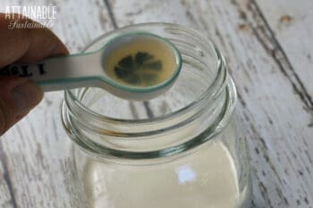ceramic measuring spoon with lemon juice over a jar of cream