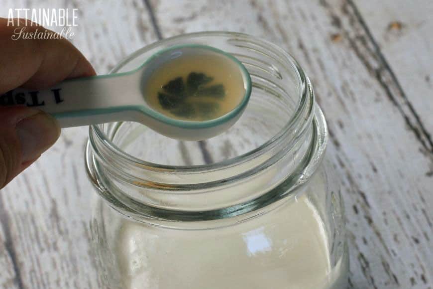 ceramic measuring spoon with lemon juice over a jar of cream